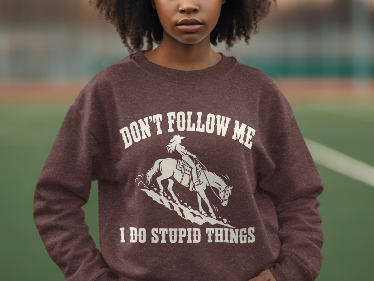 A person wearing a brown crewneck sweatshirt featuring a white graphic of a horse and rider.