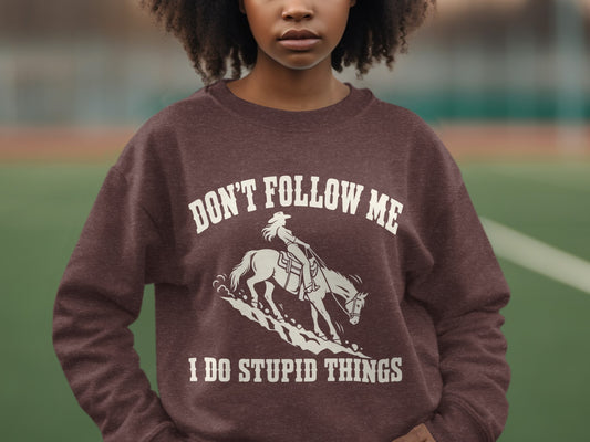 A person wearing a brown crewneck sweatshirt featuring a white graphic of a horse and rider.