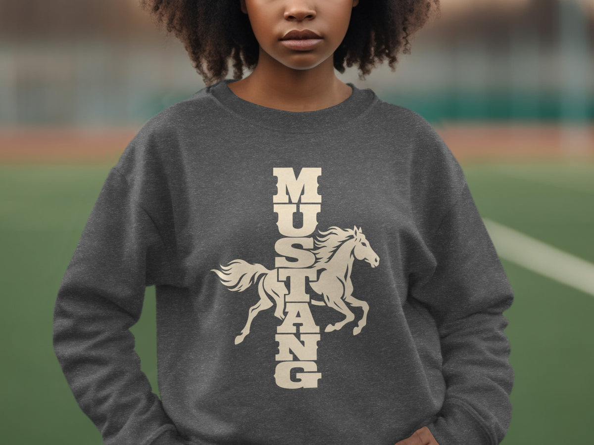A person wearing a dark grey crewneck sweatshirt featuring a graphic of a running horse and the vertical text "MUSTANG".