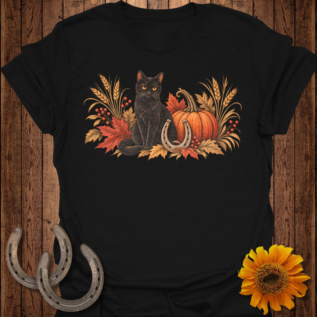 Black cat with autumn leaves, pumpkin, and horseshoe on black t-shirt.