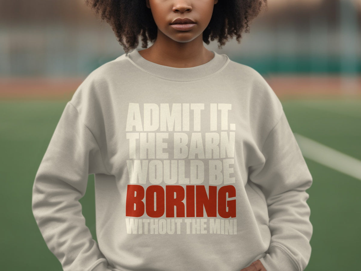 A person wearing a light gray crewneck sweatshirt with the text ADMIT IT. THE BARN WOULD BE BORING WITHOUT THE MINI printed in white and red.