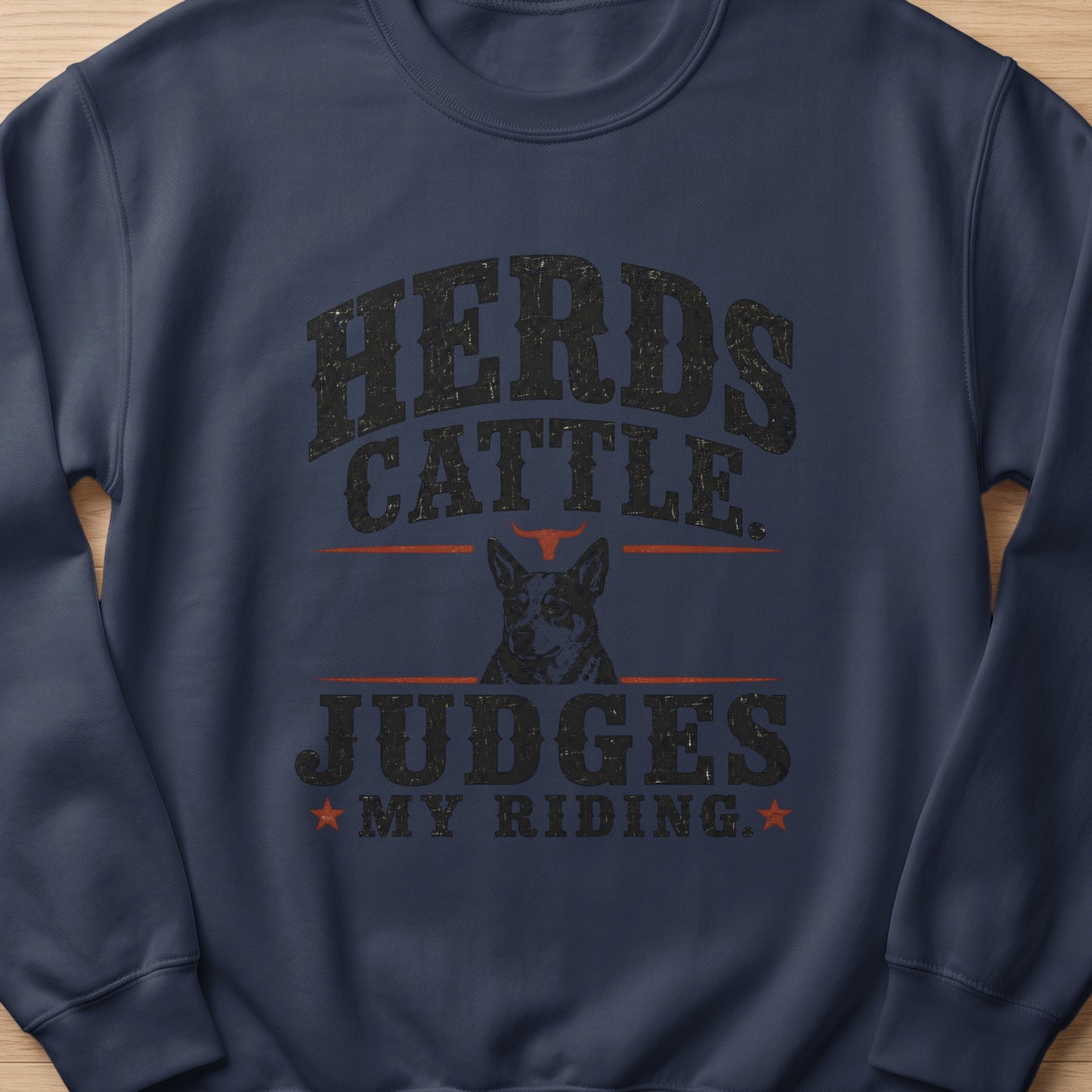 Dark blue crewneck sweatshirt with "Herds Cattle Judges My Riding" text and dog graphic.