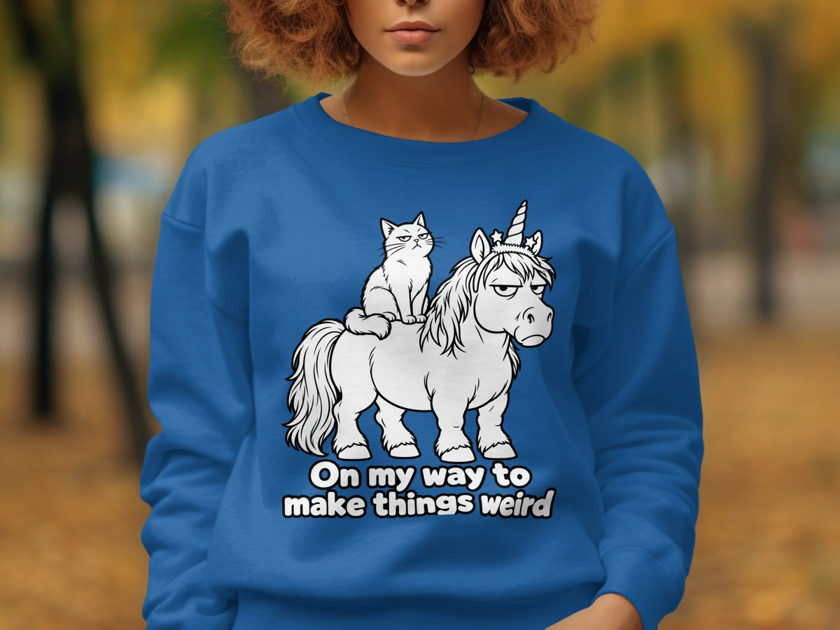 Blue sweatshirt with cartoon cat riding a grumpy unicorn and text "On my way to make things weird".