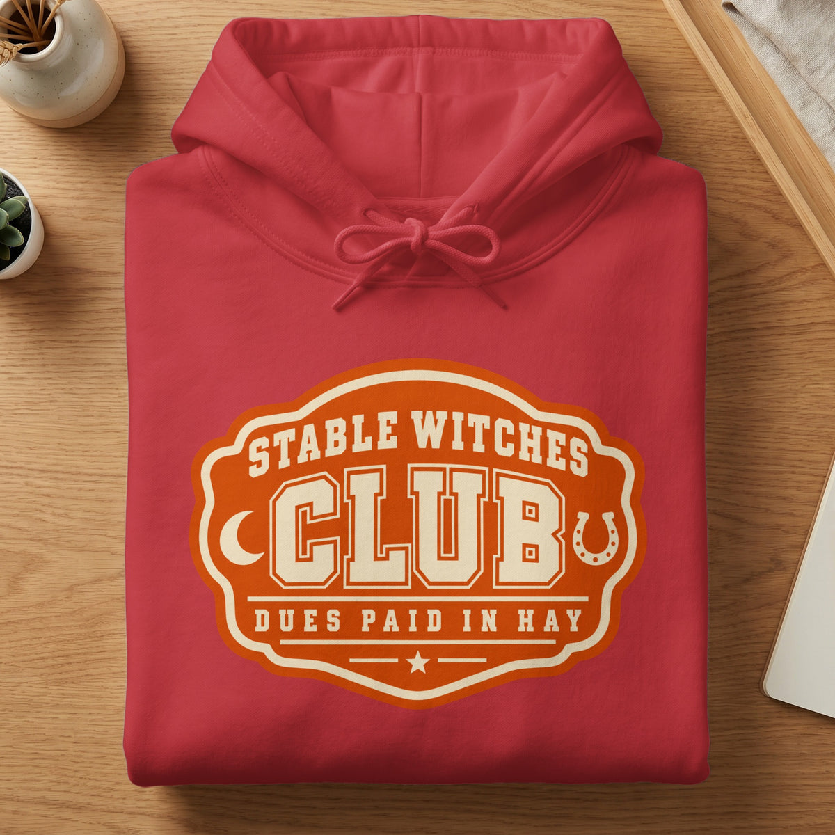Red hoodie with "Stable Witches Club" graphic and horseshoe detail.