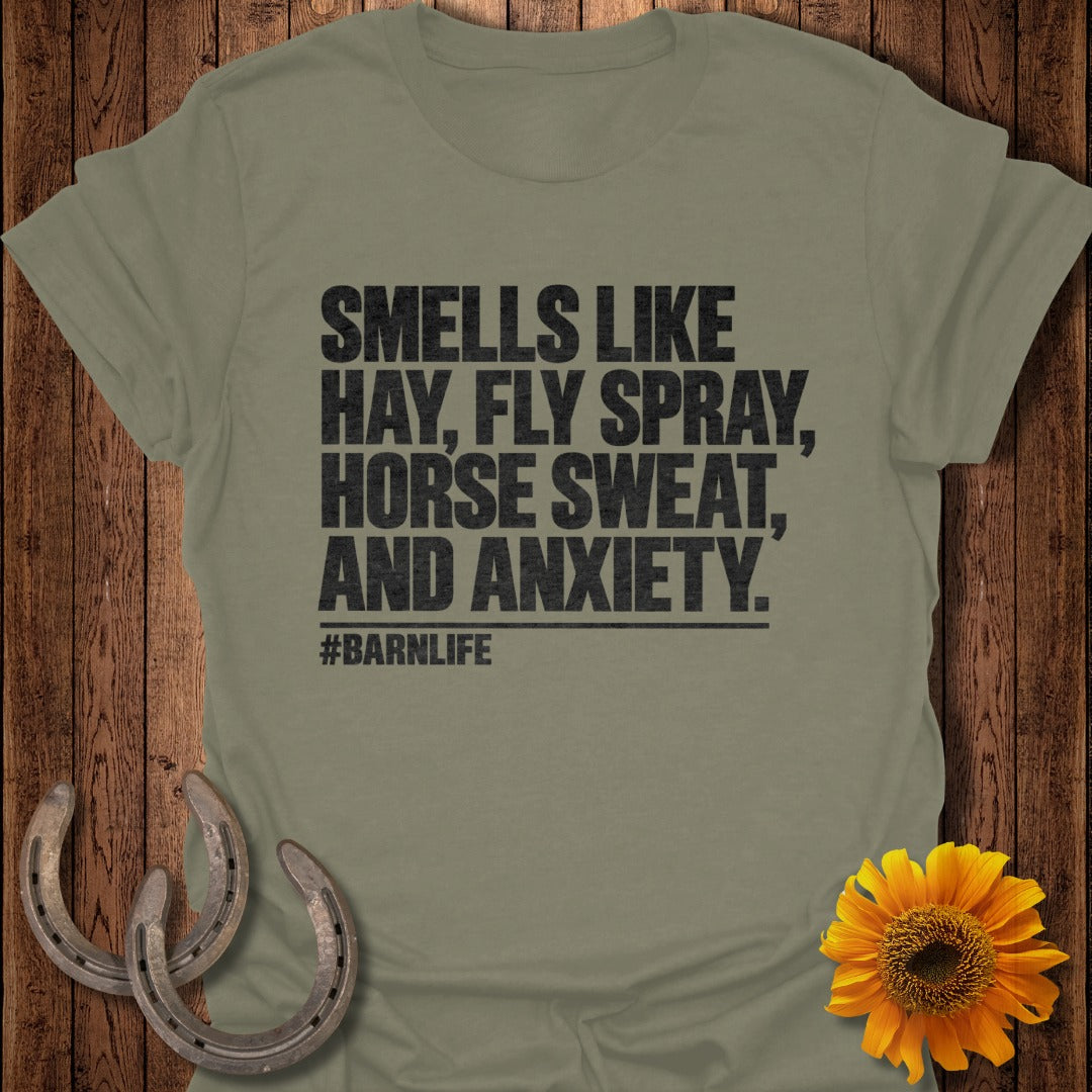 An olive green t-shirt with black text reading smells like hay, fly spray, horse sweat, and anxiety.