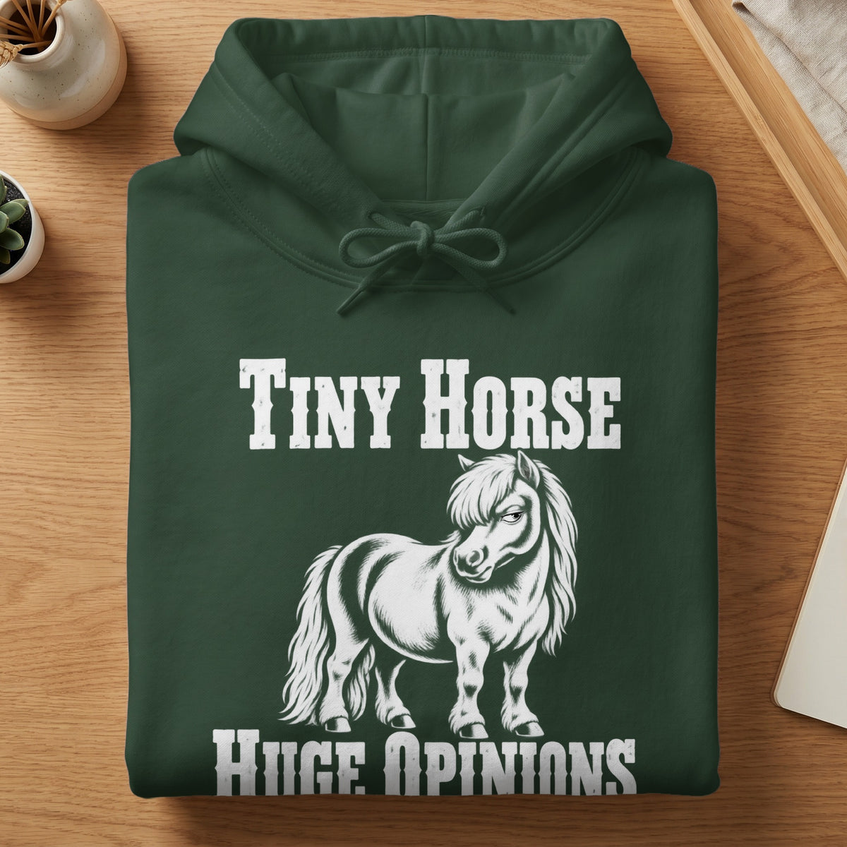 A dark green hooded sweatshirt with white text that reads Tiny Horse Huge Opinions above and below a graphic of a pony.