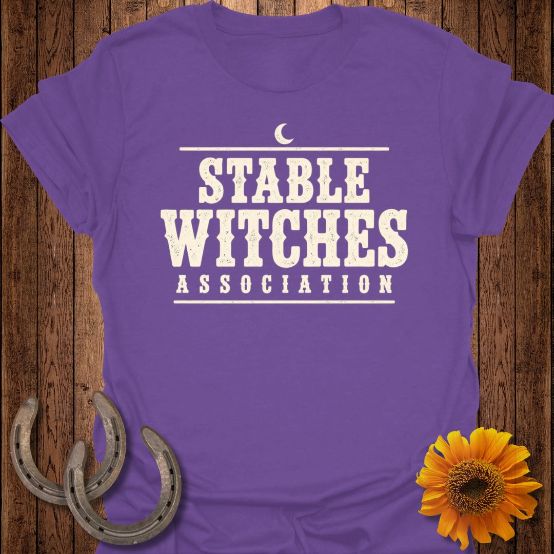 Purple t-shirt with "Stable Witches Association" text and a crescent moon graphic.