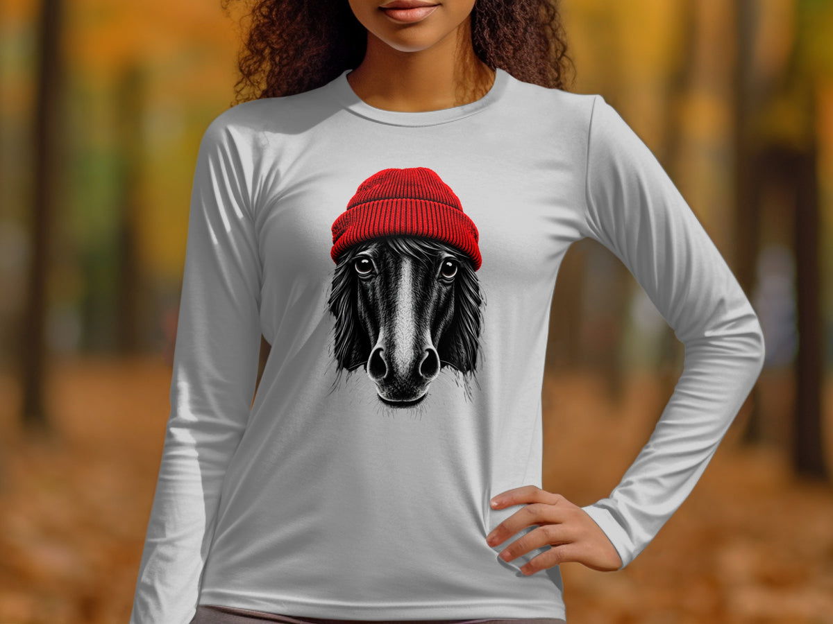 A person wearing a long-sleeved gray t-shirt printed with a black horse wearing a red beanie.