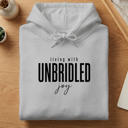 White hoodie with "living with UNBRIDLED joy" text on the front.