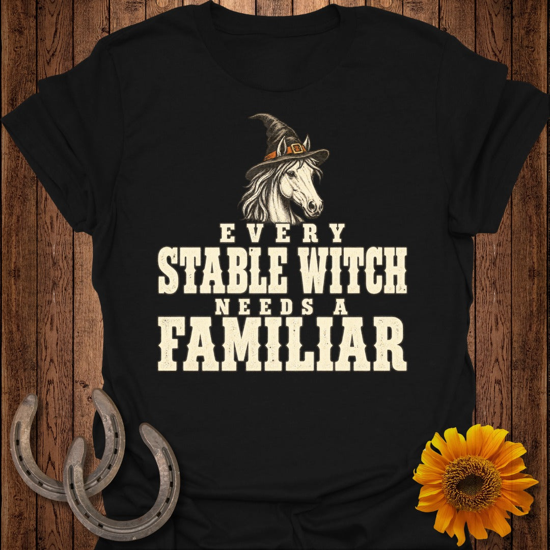 Black t-shirt with white text "EVERY STABLE WITCH NEEDS A FAMILIAR" and a horse in a witch hat.