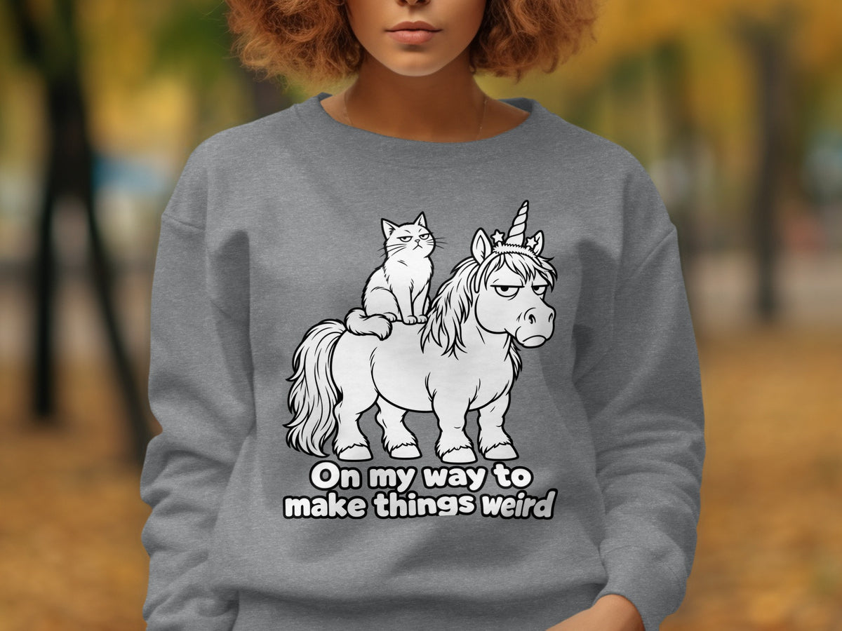 Graphic of a grumpy unicorn with a cat on its back and text that says "On my way to make things weird".