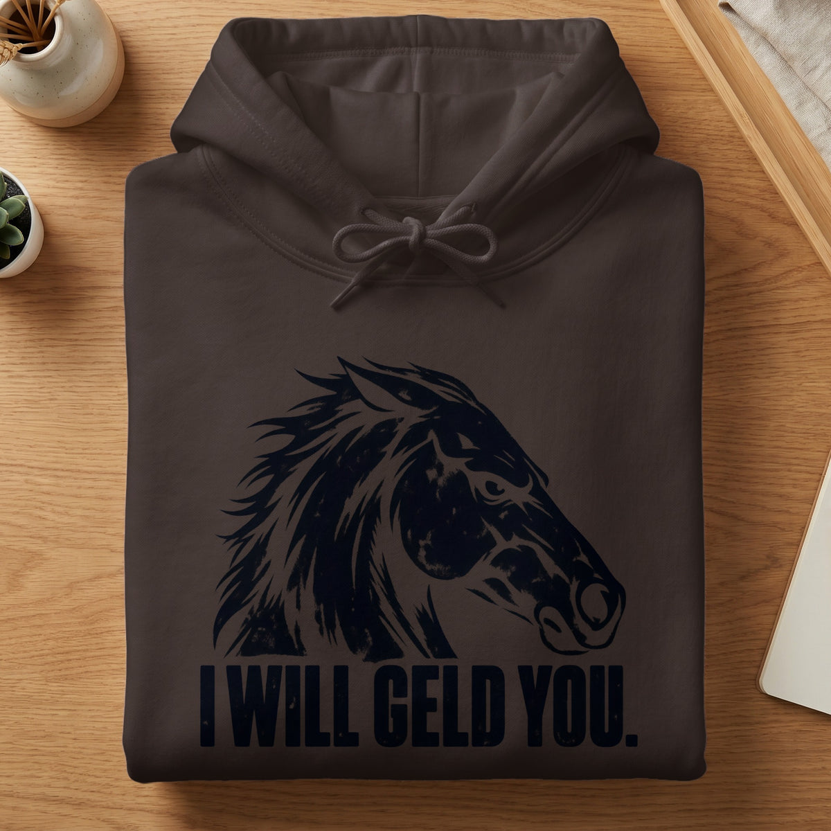 A folded dark brown hoodie with a black horse graphic and the text I WILL GELD YOU.