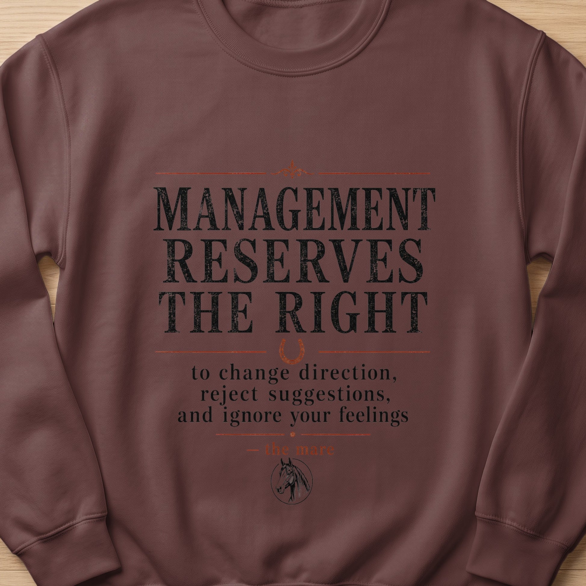 Brown sweatshirt with text: "MANAGEMENT RESERVES THE RIGHT to change direction, reject suggestions, and ignore your feelings — the mare."