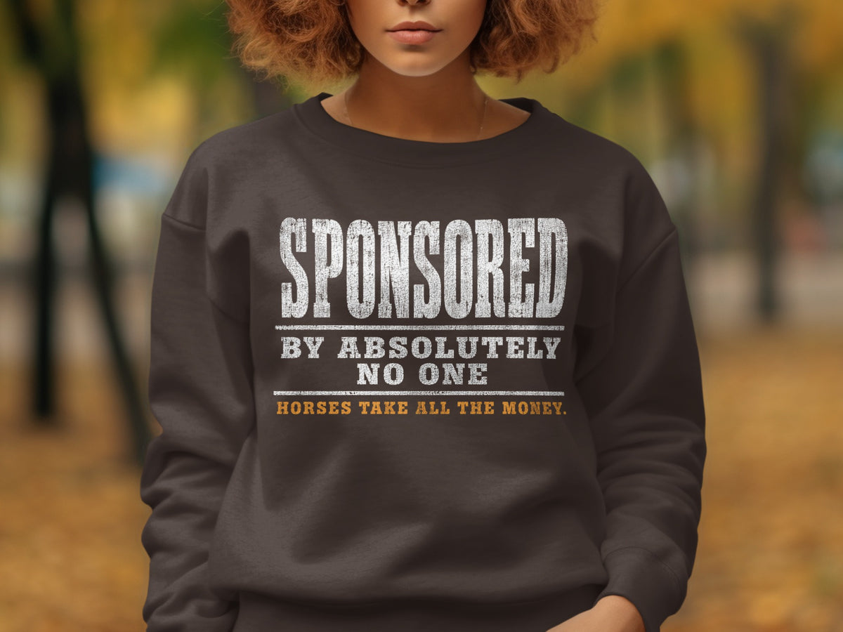 Dark brown sweatshirt with distressed white text "SPONSORED BY ABSOLUTELY NO ONE" and yellow text "HORSES TAKE ALL THE MONEY."