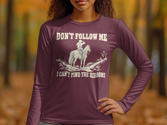 A person wearing a plum-colored long-sleeve shirt featuring an equestrian graphic and humorous text.