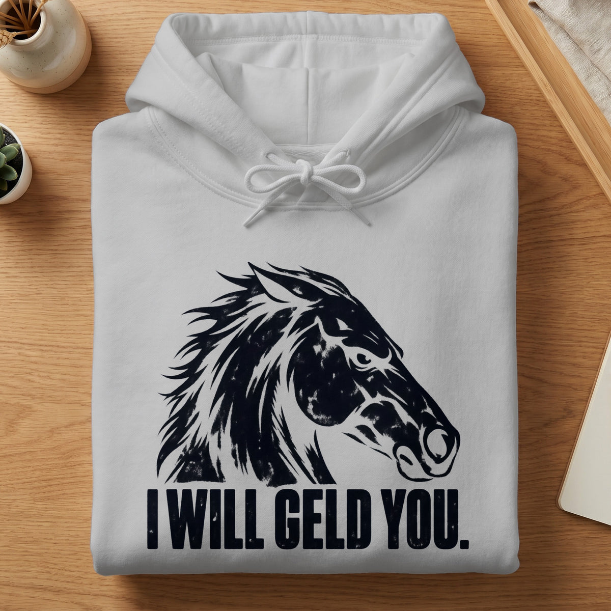 A folded white hoodie with a black horse graphic and text reading I WILL GELD YOU.