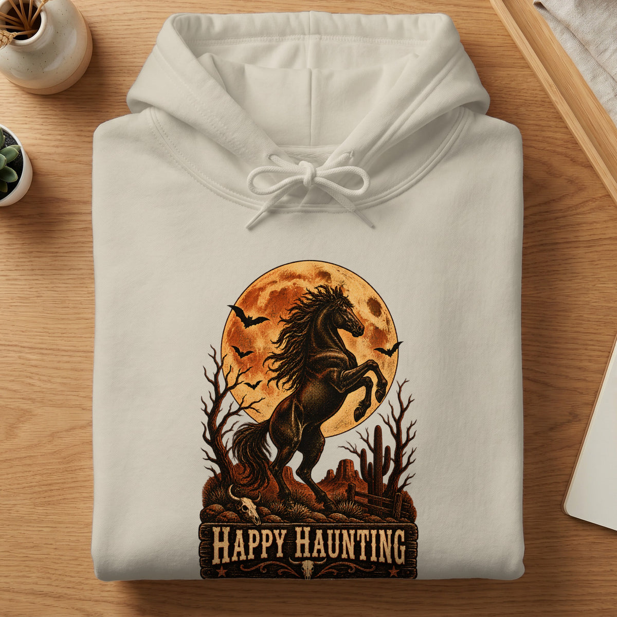 Cream hoodie with a Halloween-themed graphic of a horse, moon, bats, and desert landscape.