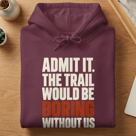 A folded plum-colored hoodie rests on a wooden surface, featuring the white text "ADMIT IT. THE TRAIL WOULD BE" with the word "BORING" in red and "WITHOUT US" in white below.