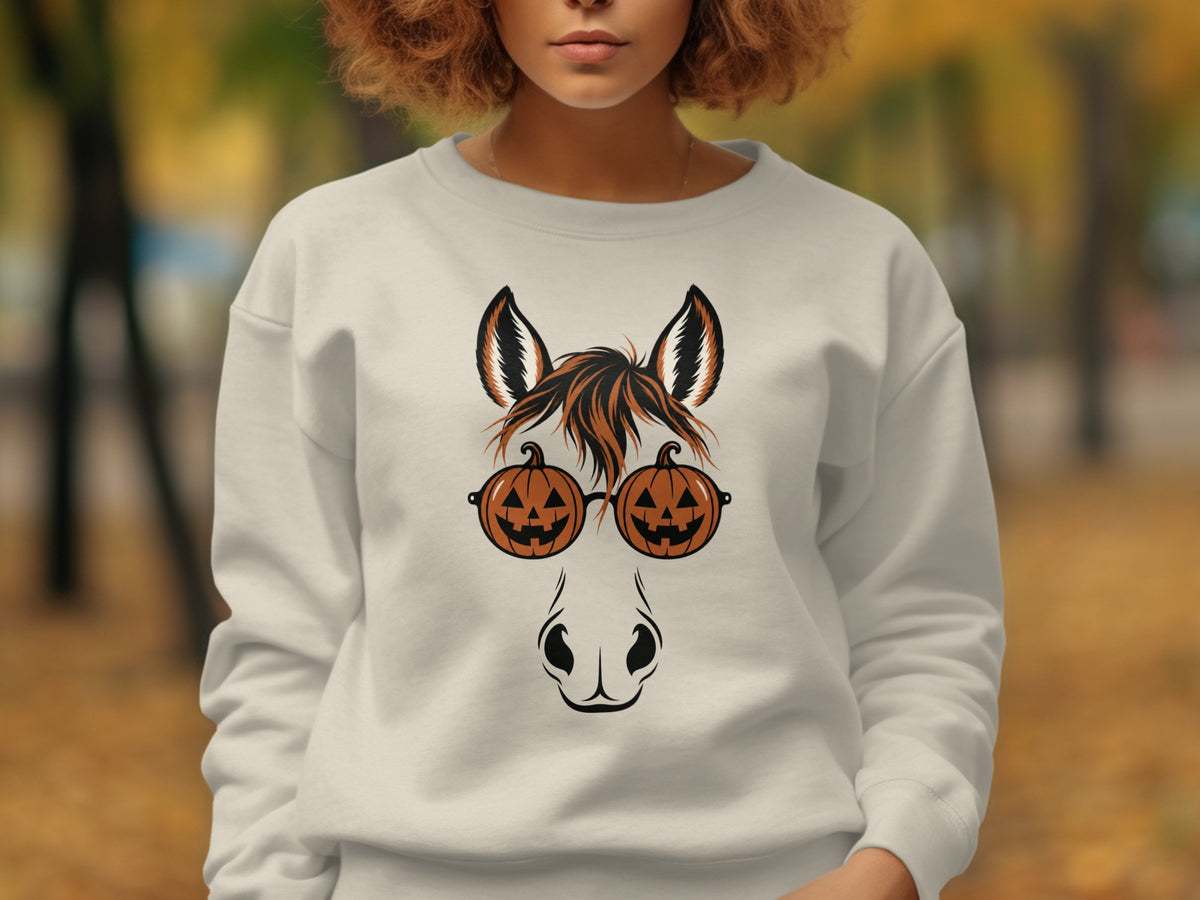 Horse wearing pumpkin-shaped glasses with Halloween theme on a cream sweatshirt.