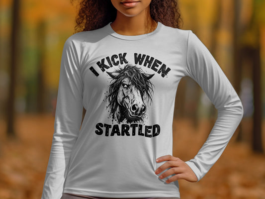 White long-sleeve shirt with "I KICK WHEN STARTLED" and horse graphic.