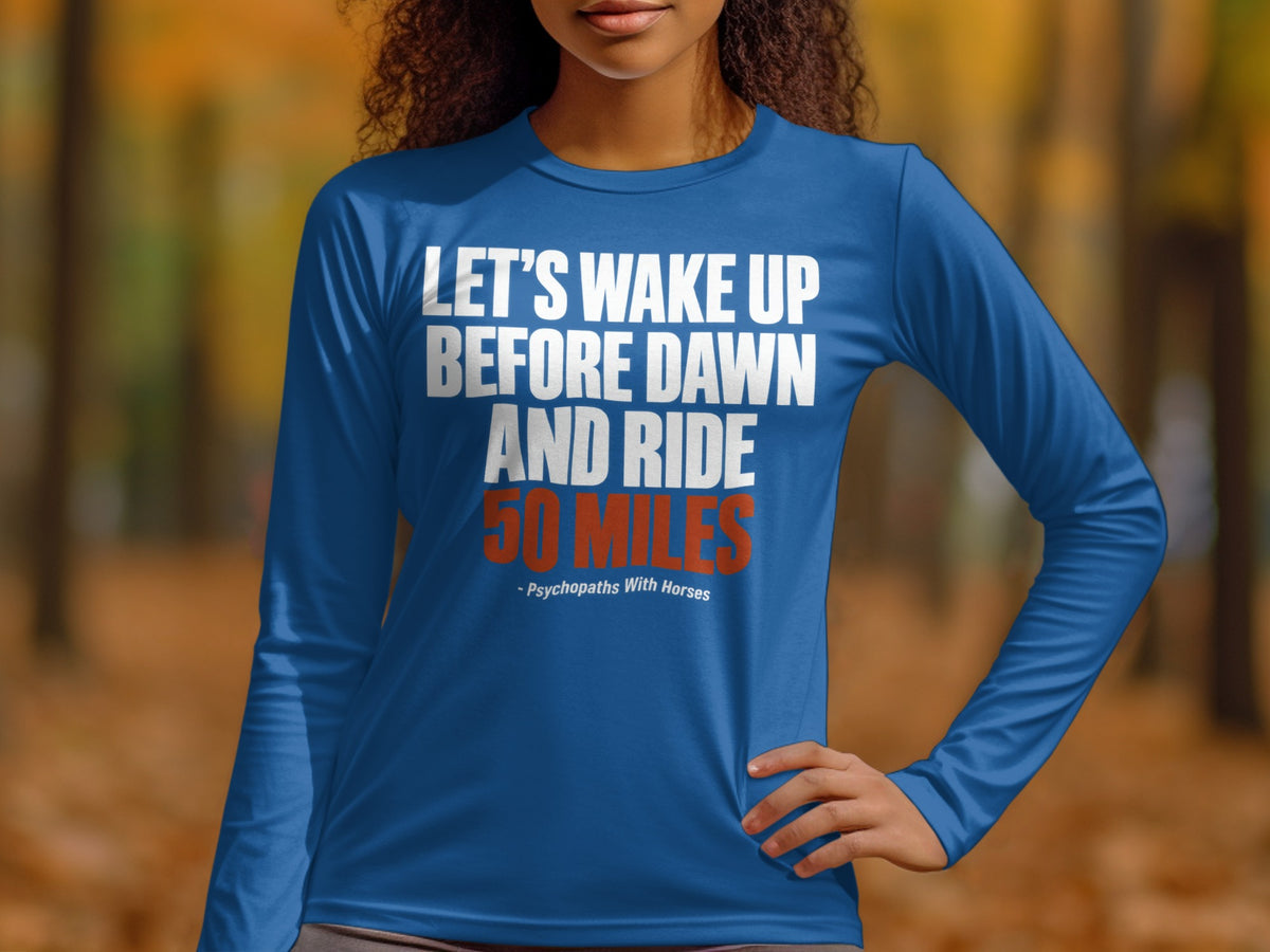A person wearing a long-sleeved blue shirt with white and orange text reading Let's wake up before dawn and ride 50 miles.
