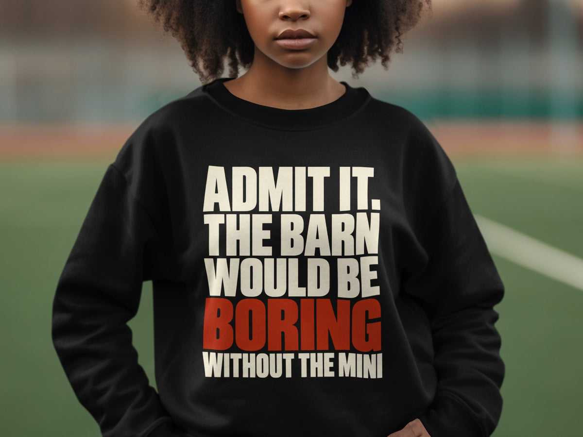 A person wearing a black crewneck sweatshirt with the white and red text, ADMIT IT. THE BARN WOULD BE BORING WITHOUT THE MINI.