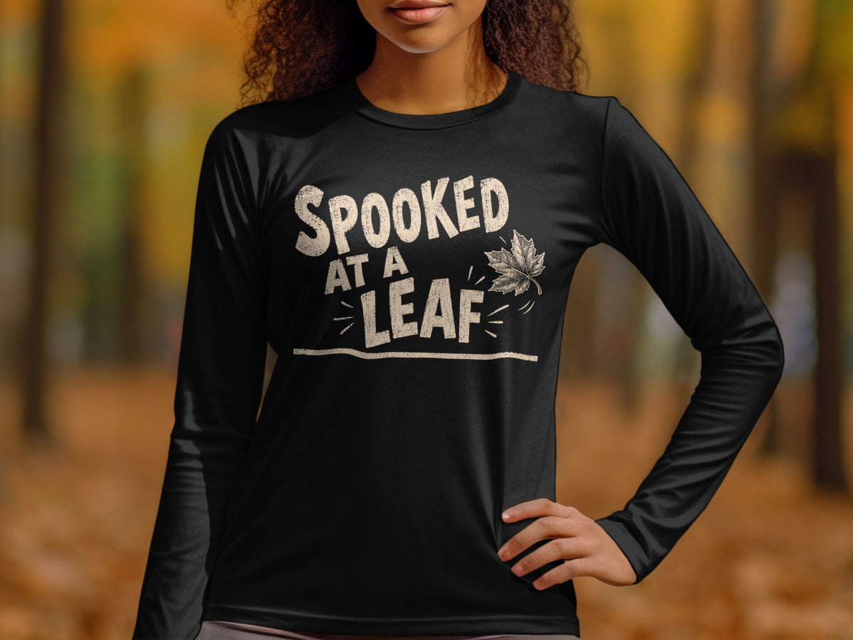 Black long sleeve shirt with "SPOOKED AT A LEAF" text and a falling leaf graphic.
