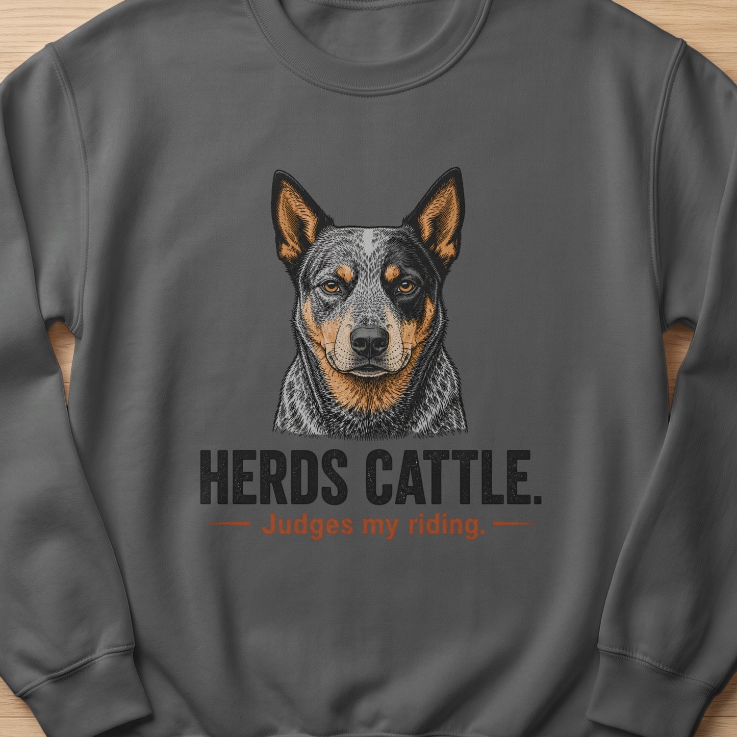Dark grey sweatshirt with an Australian Cattle Dog portrait and text "HERDS CATTLE. Judges my riding."