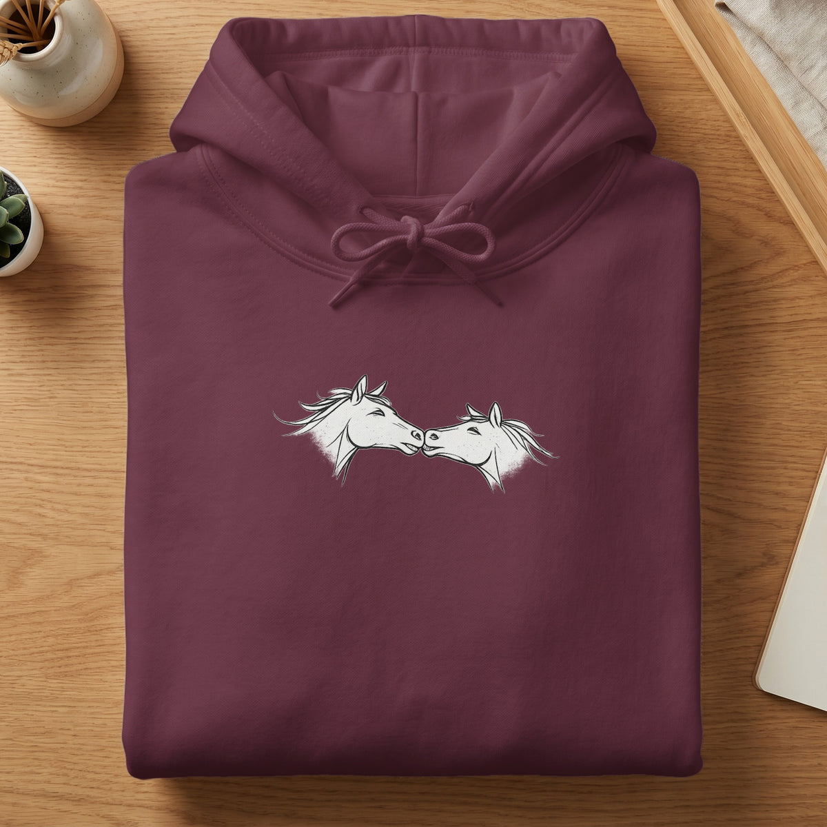 Maroon hoodie with a white line drawing of two horses' heads touching.