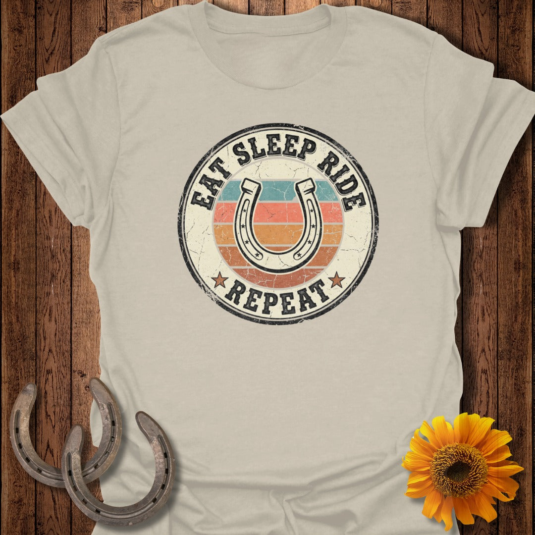 Cream t-shirt with "Eat Sleep Ride Repeat" horseshoe graphic and sunburst.