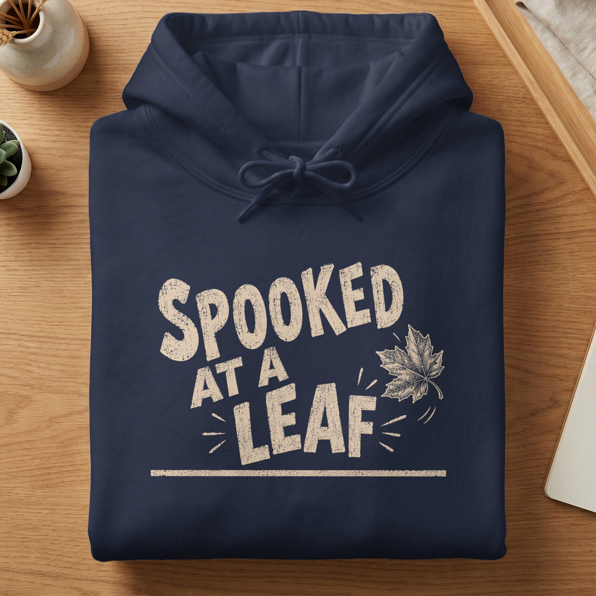 Navy hoodie with distressed text "SPOOKED AT A LEAF" and a drawing of a falling leaf.