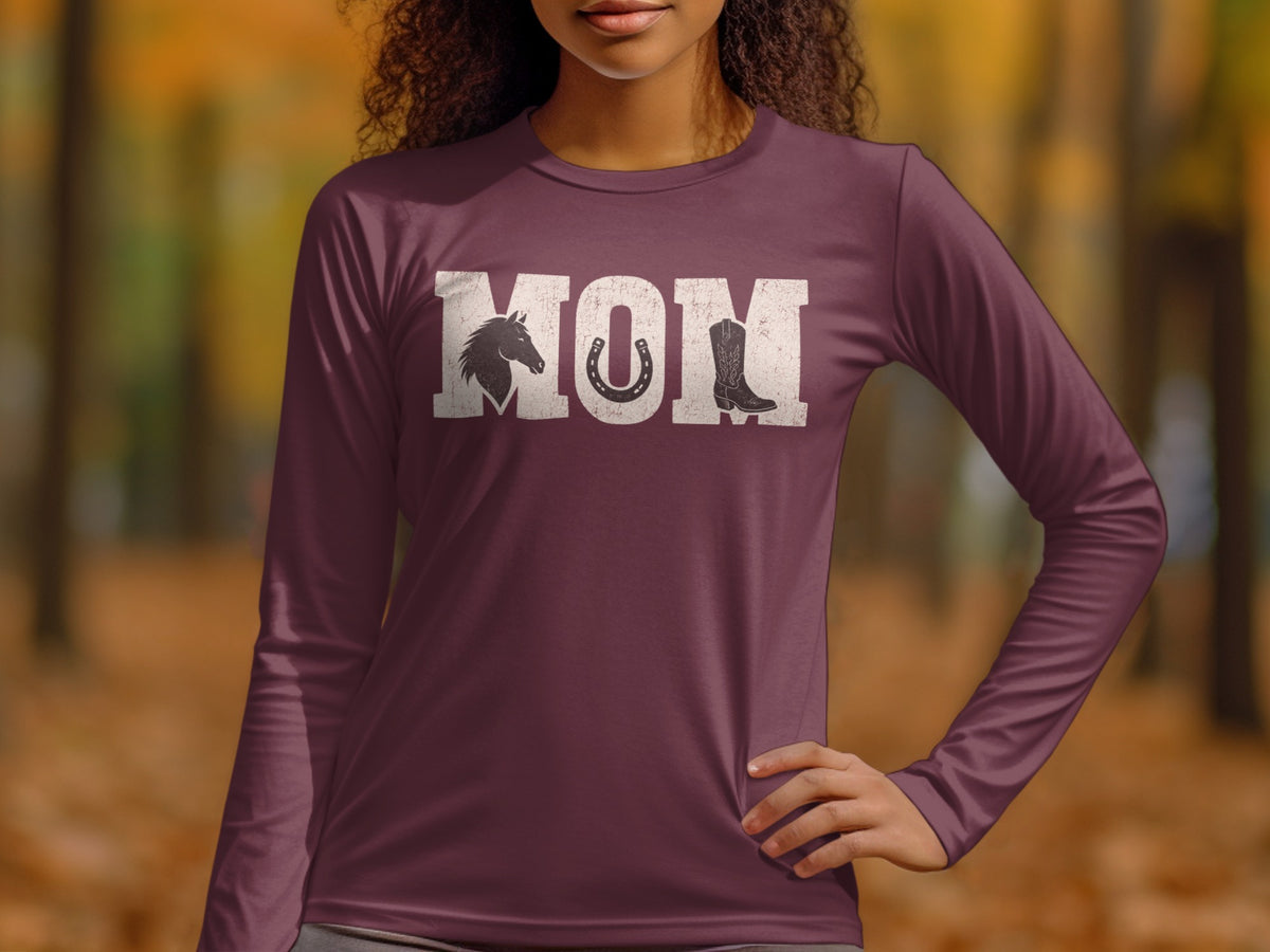 A person wearing a plum-colored long-sleeve shirt with the distressed white text MOM, incorporating a horse head, horseshoe, and cowboy boot.