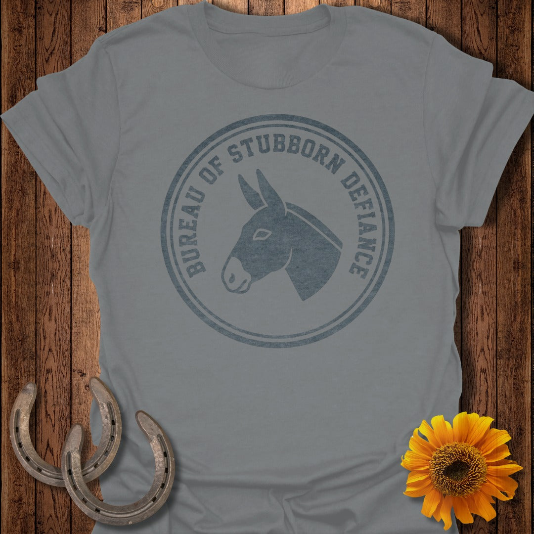 Grey t-shirt with "Bureau of Stubborn Defiance" circular logo and donkey head graphic.