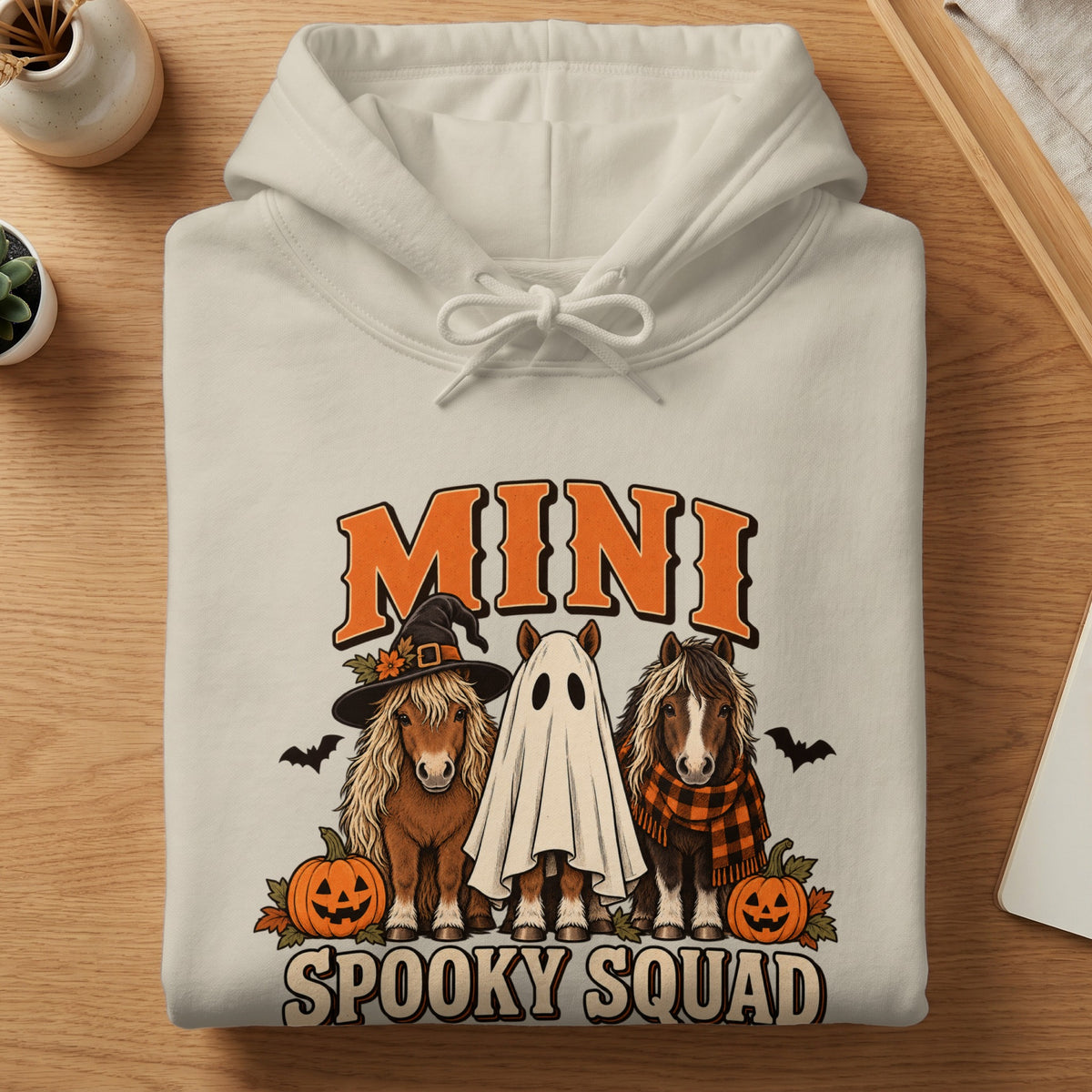 Cream hoodie with "Mini Spooky Squad" text and three horses in Halloween costumes.