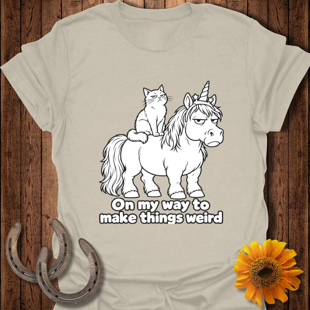 A tan t-shirt features a grumpy cat riding a grumpy unicorn, with text reading "On my way to make things weird".