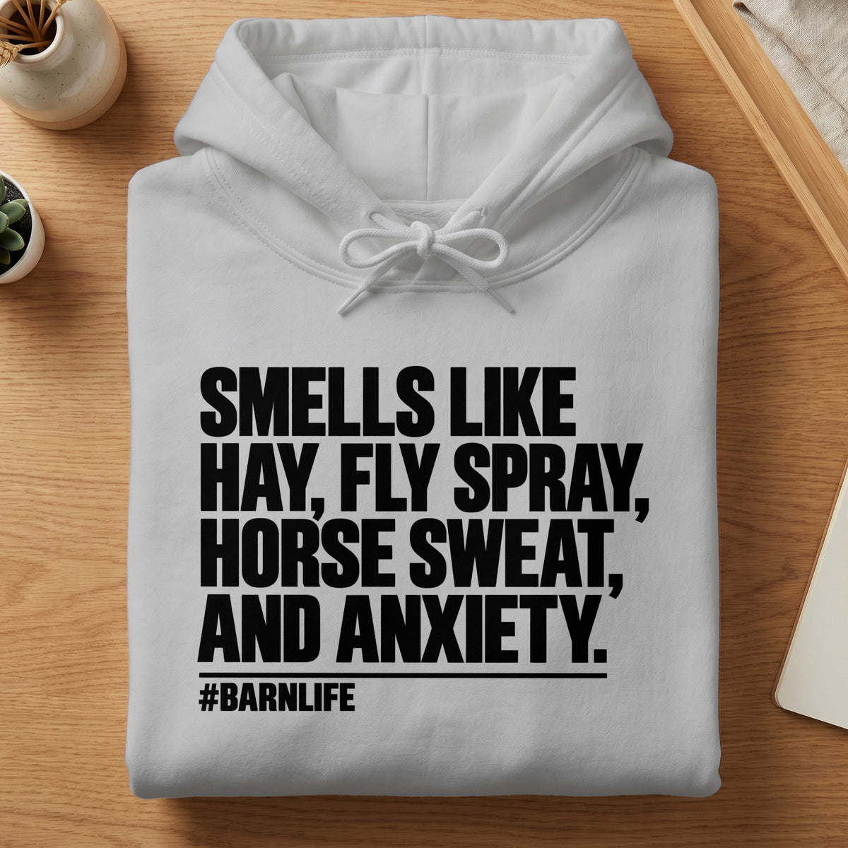 White hoodie with black text: Smells like hay, fly spray, horse sweat, and anxiety. #Barnlife.