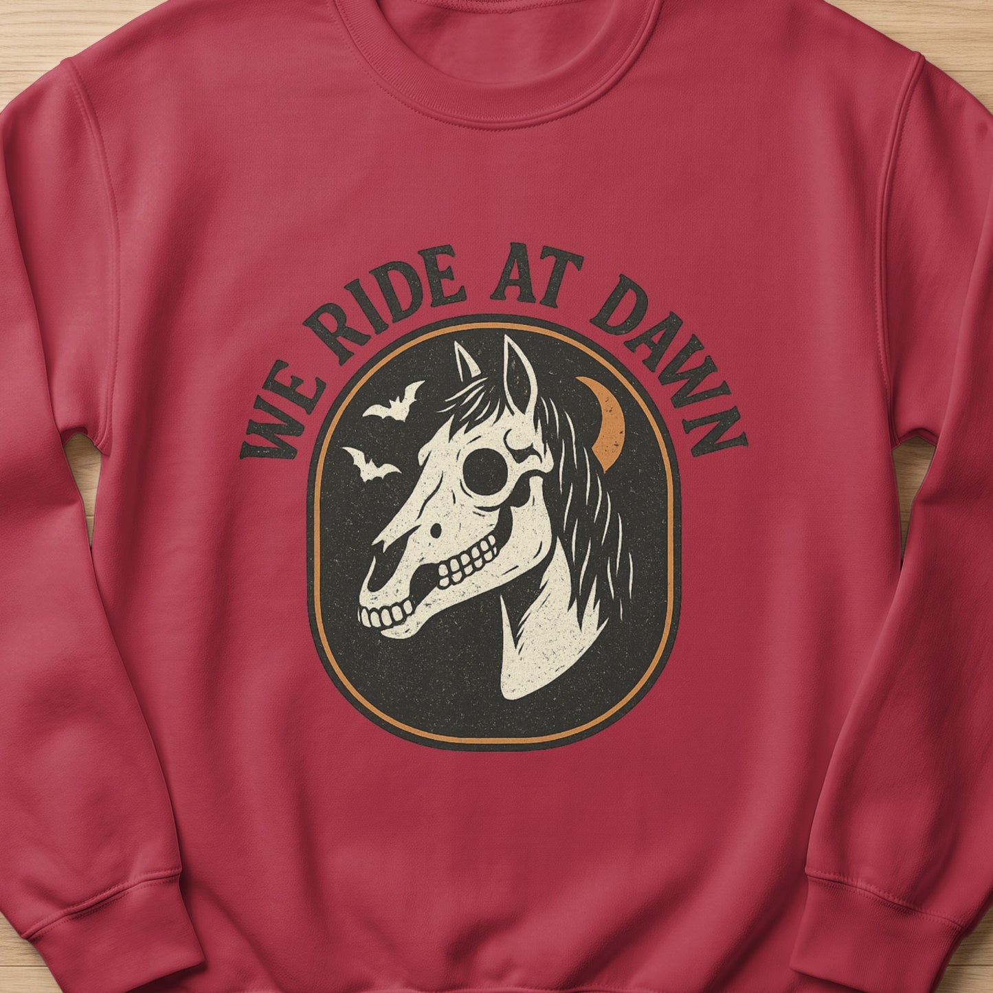 Red sweatshirt with "We Ride at Dawn" text and a skull horse graphic.