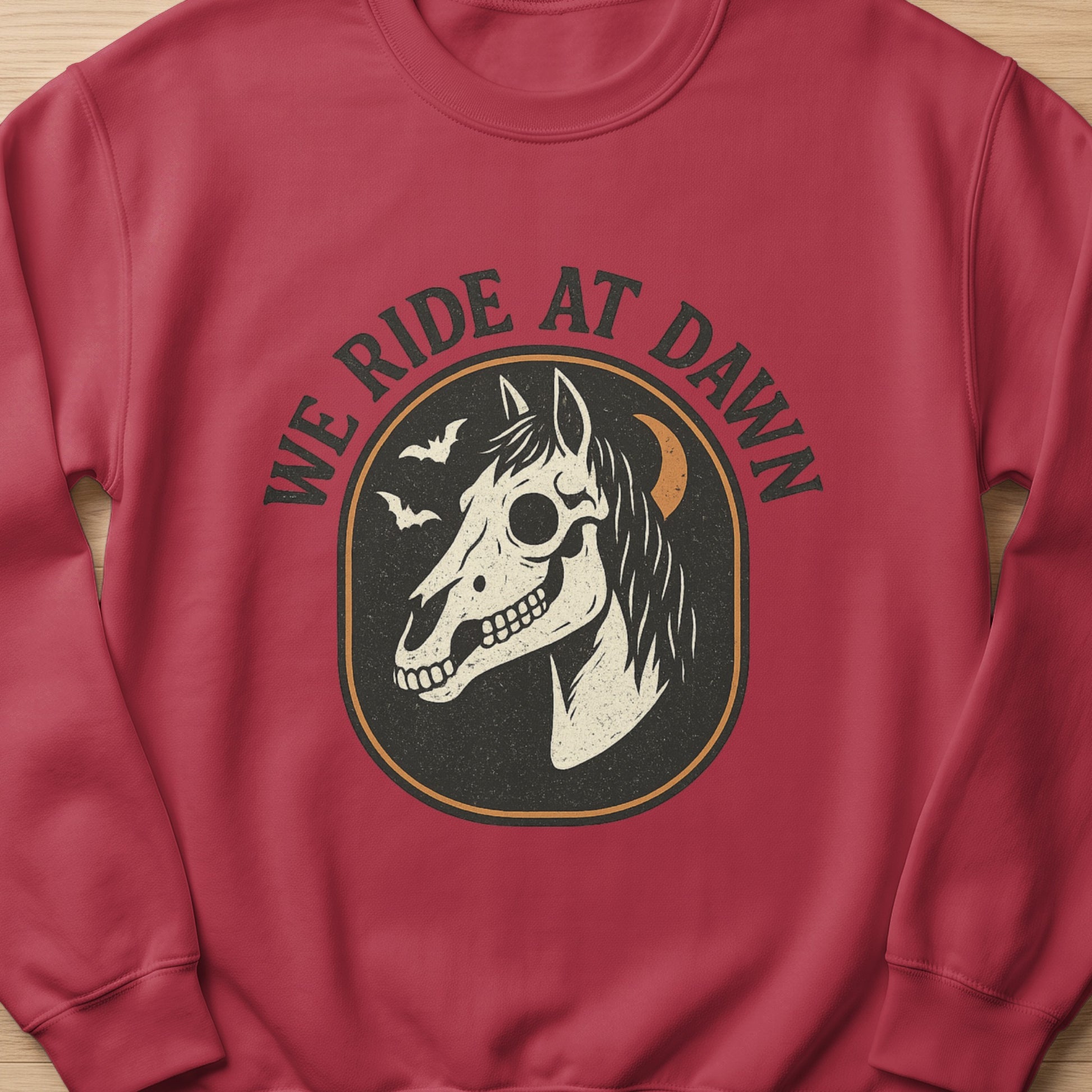 Red sweatshirt with "We Ride at Dawn" text and a skull horse graphic.