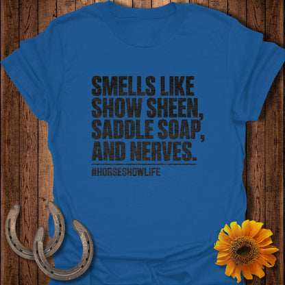 A blue t-shirt printed with the text SMELLS LIKE SHOW SHEEN, SADDLE SOAP, AND NERVES.