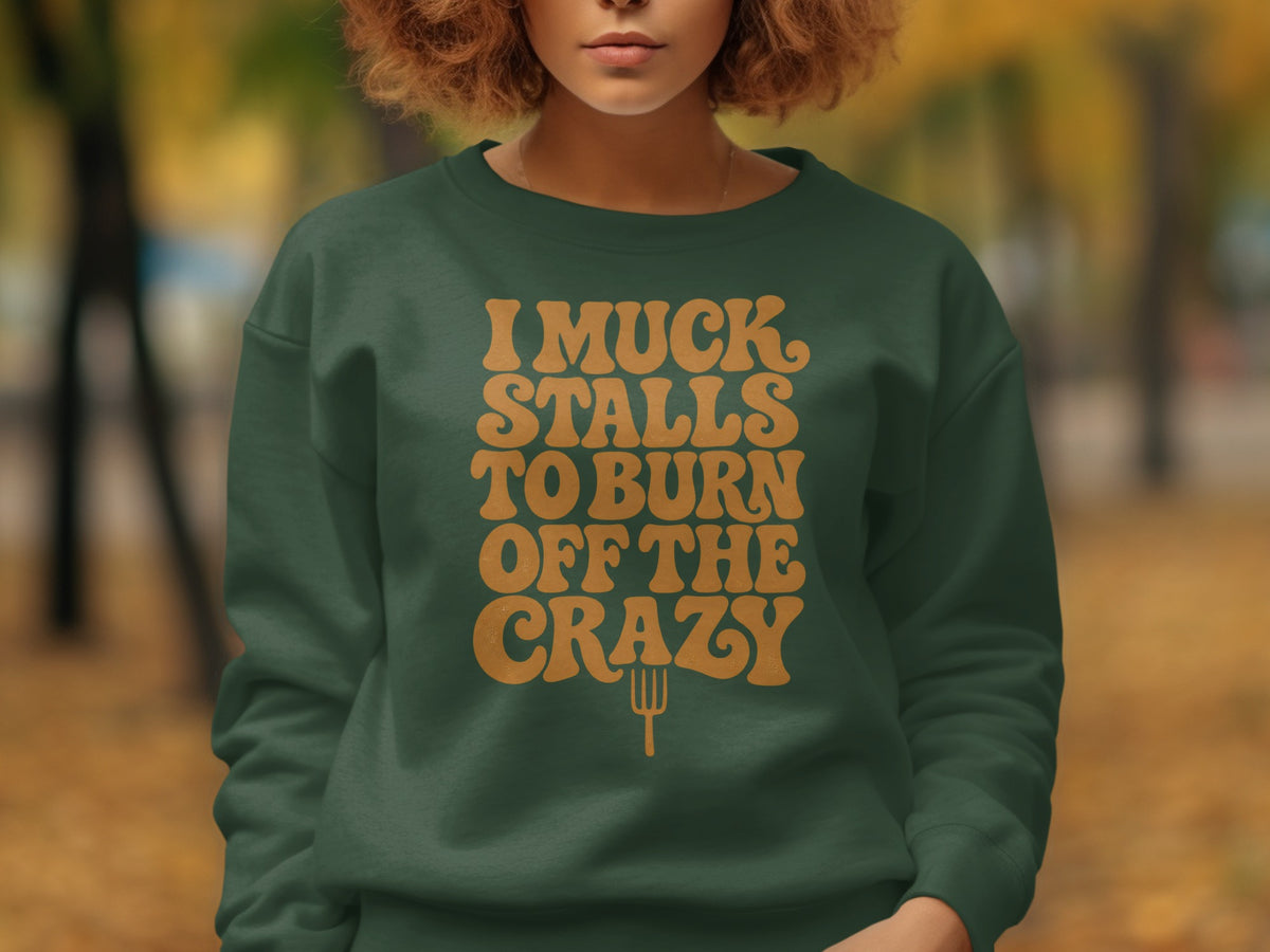 Green sweatshirt with orange text "I MUCK STALLS TO BURN OFF THE CRAZY" and a pitchfork.