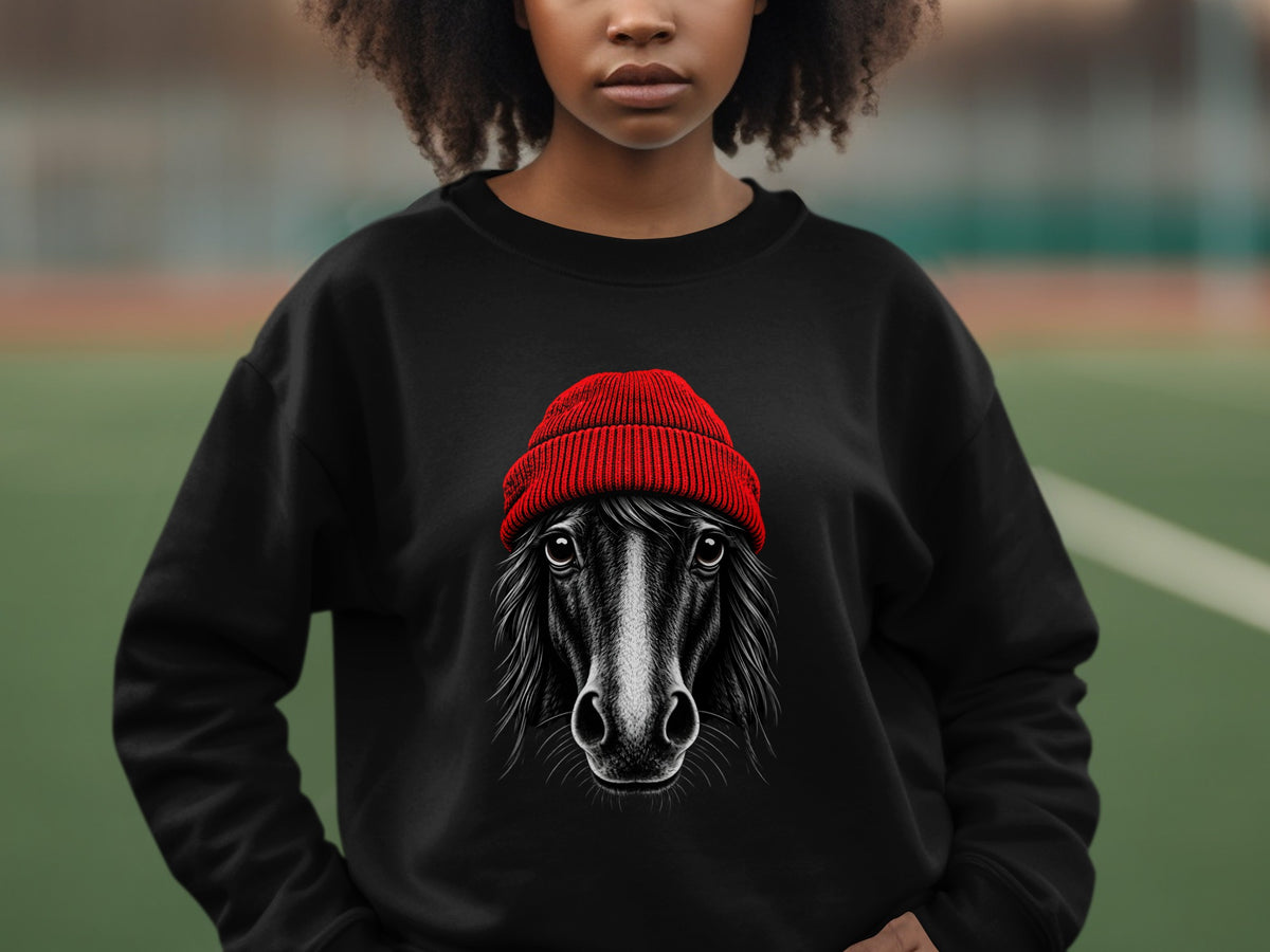 A person wearing a black crewneck sweatshirt featuring a graphic of a black horse wearing a red beanie.