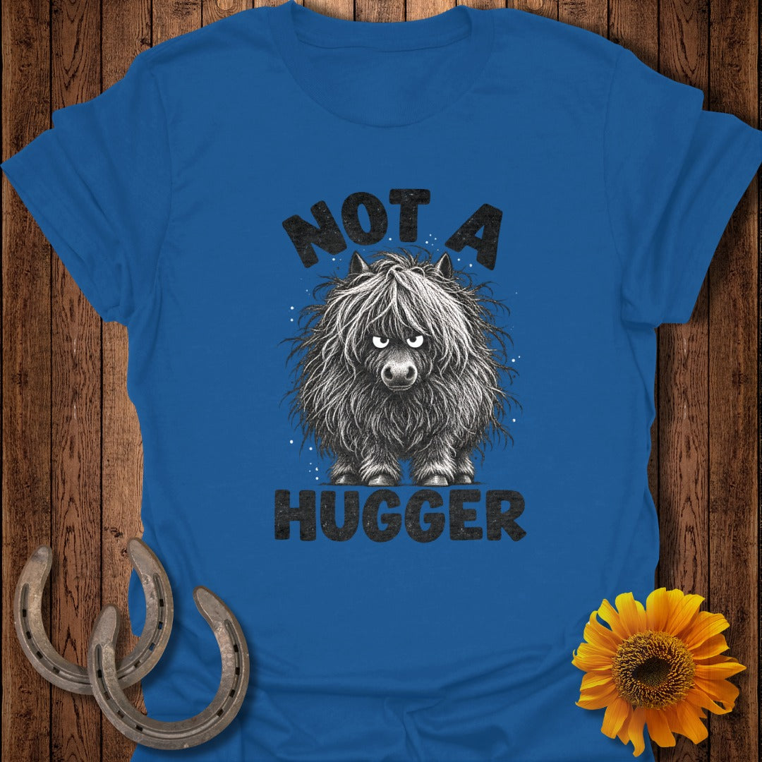 A blue t-shirt featuring a grumpy, shaggy Highland cow illustration with the text NOT A HUGGER.