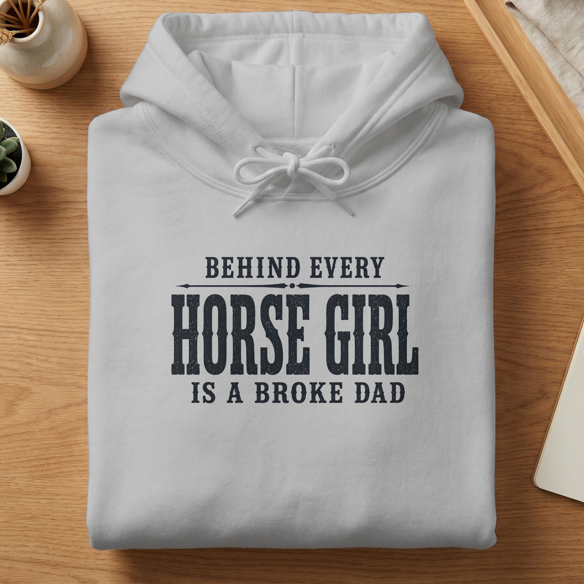 White hoodie with text: "BEHIND EVERY HORSE GIRL IS A BROKE DAD".