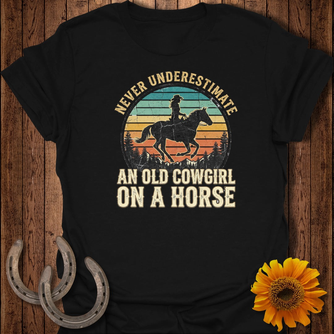 Black t-shirt with "Never Underestimate An Old Cowgirl On A Horse" text and a cowboy riding a horse.