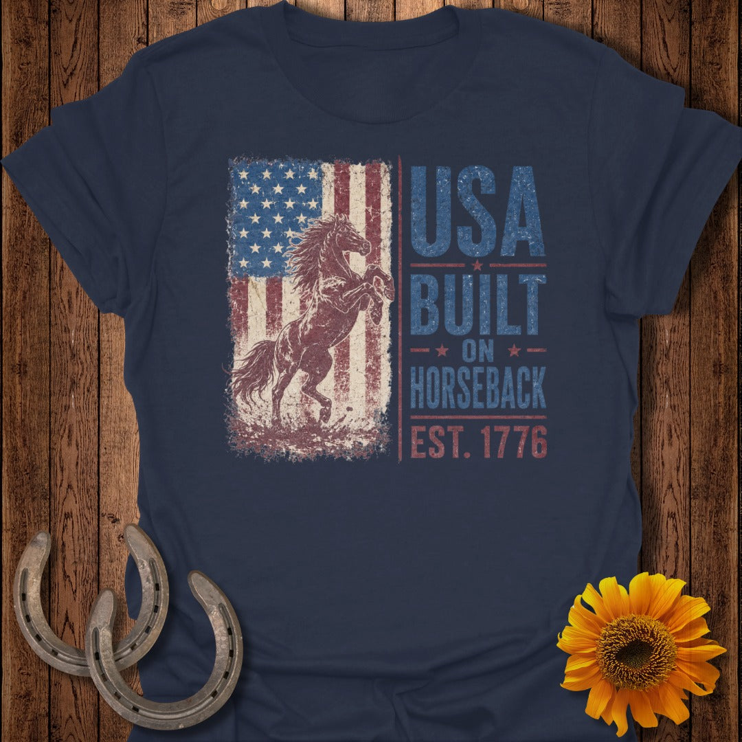 Navy t-shirt with a distressed American flag and rearing horse graphic reading "USA Built On Horseback Est. 1776".