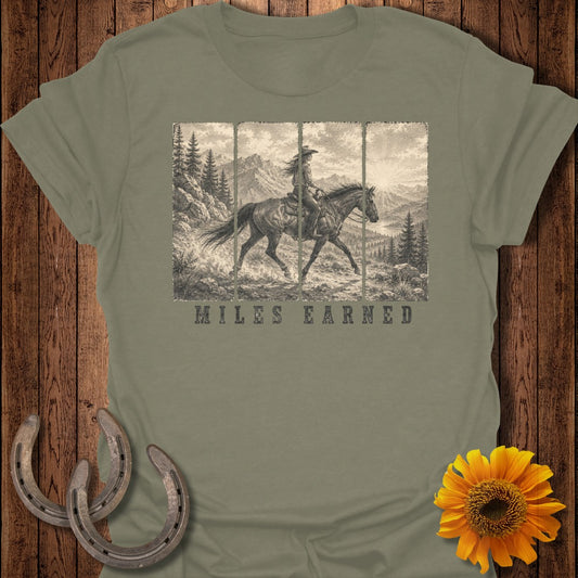 T-shirt with a vintage western scene of a woman on horseback and the text "MILES EARNED".
