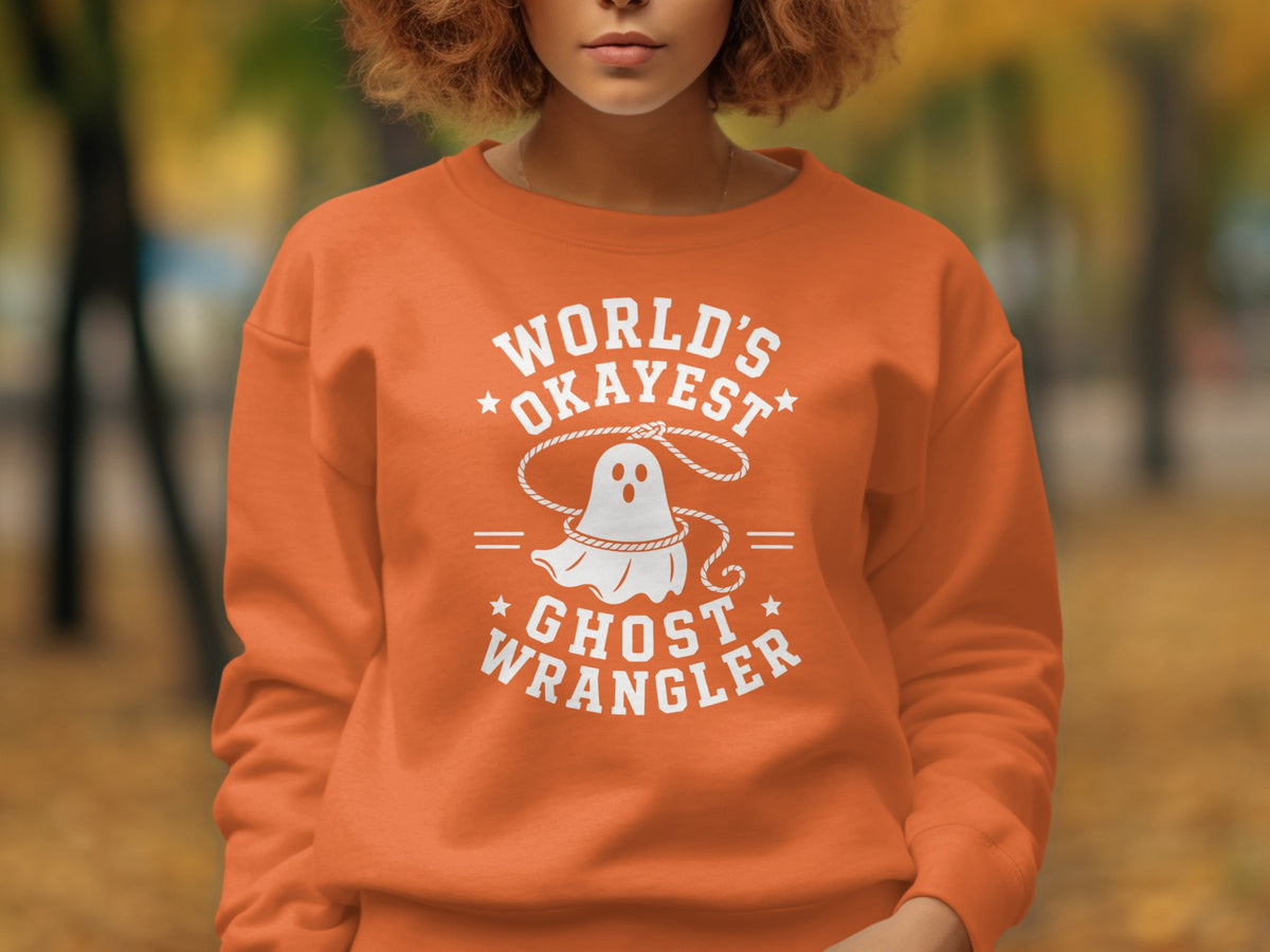 Orange sweatshirt with white "World's Okayest Ghost Wrangler" text and ghost graphic.