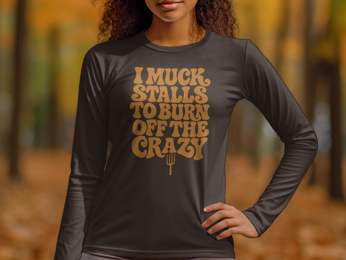 Dark long sleeve shirt with text "I muck stalls to burn off the crazy."