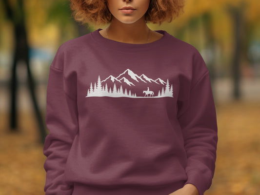 Maroon sweatshirt with white mountain, tree, and horseback rider silhouette graphic.