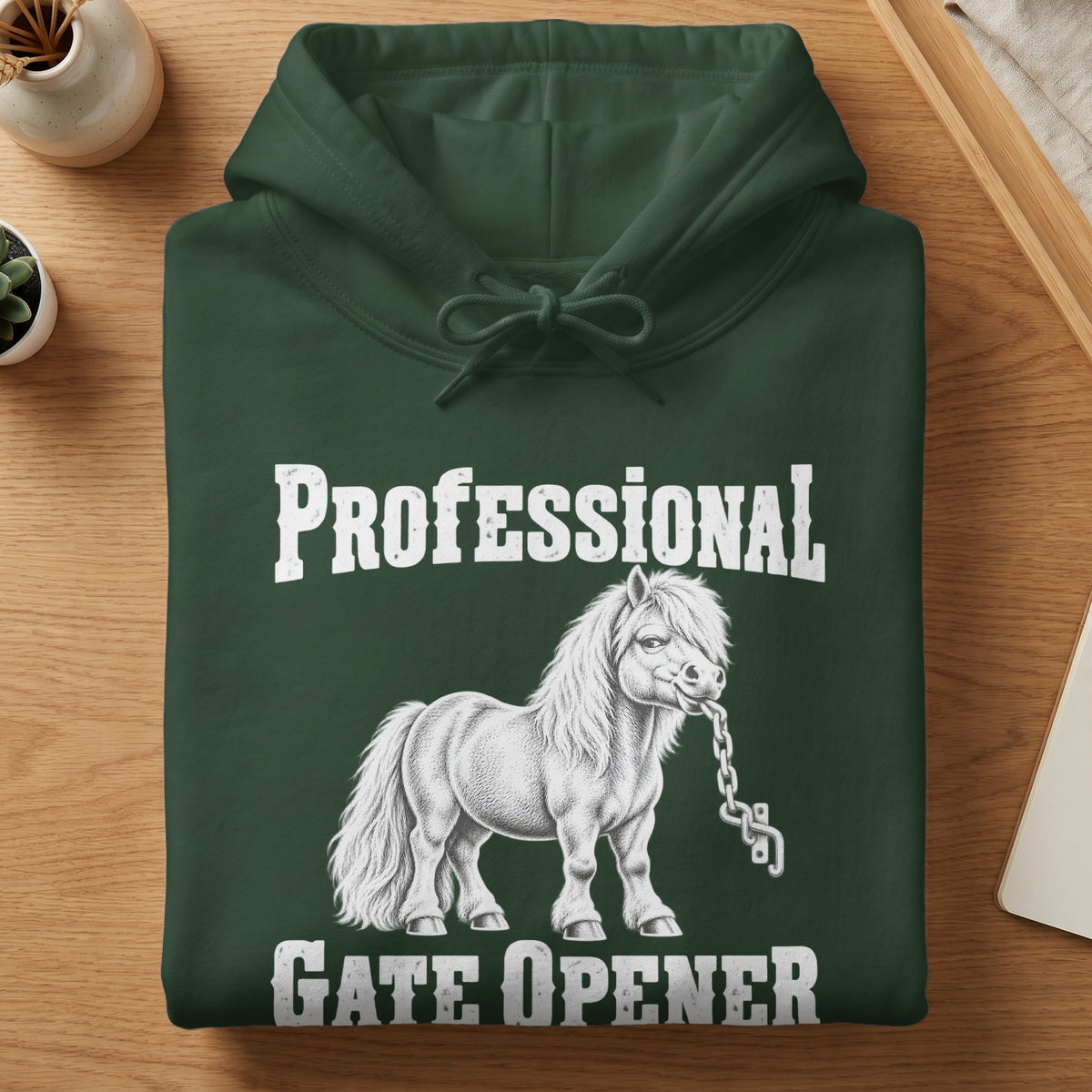 A folded dark green hooded sweatshirt with white text reading "Professional Gate Opener" and an illustration of a pony biting a chain.